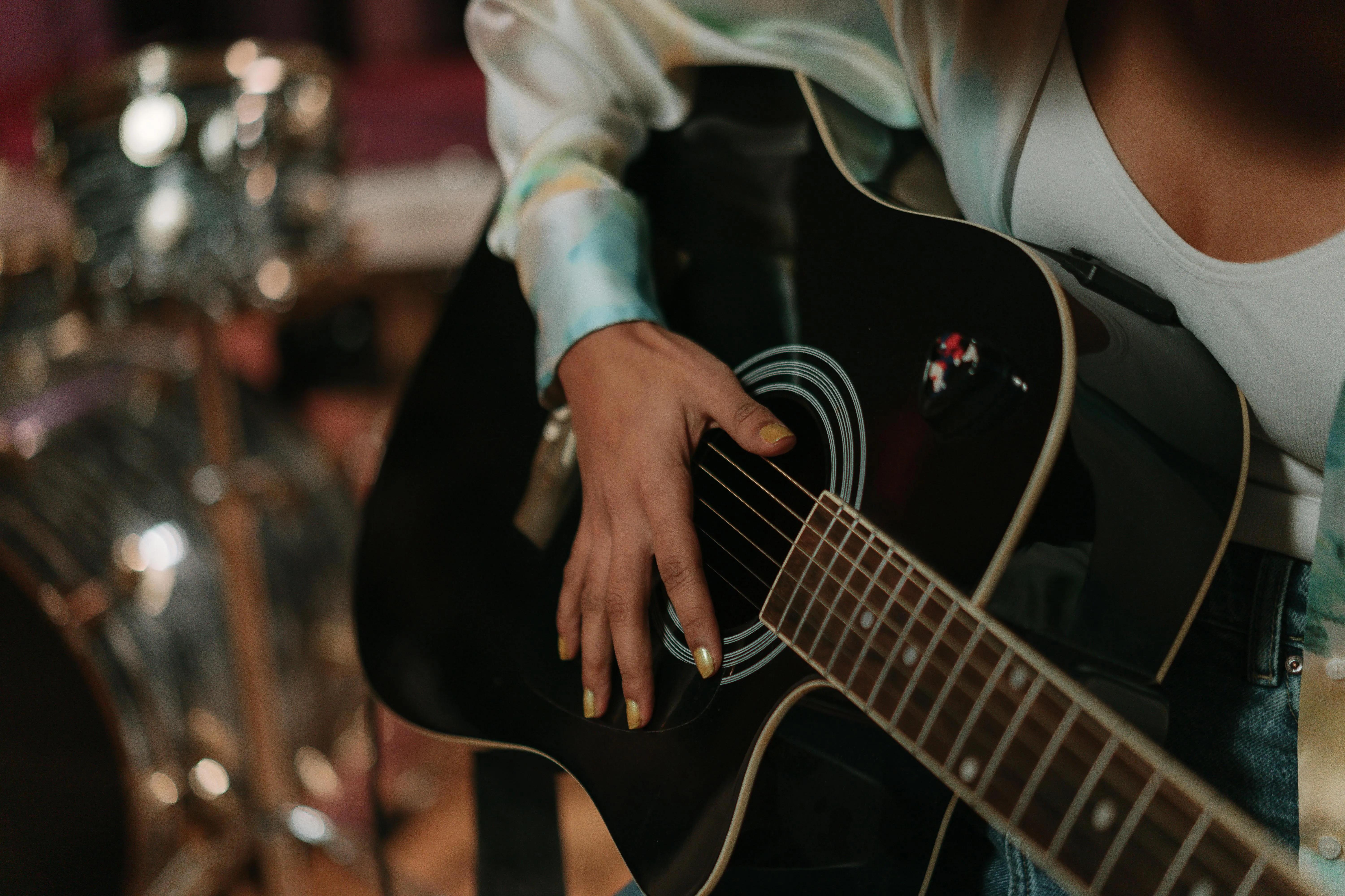 Hands playing a black acoustic guitar in a studio
