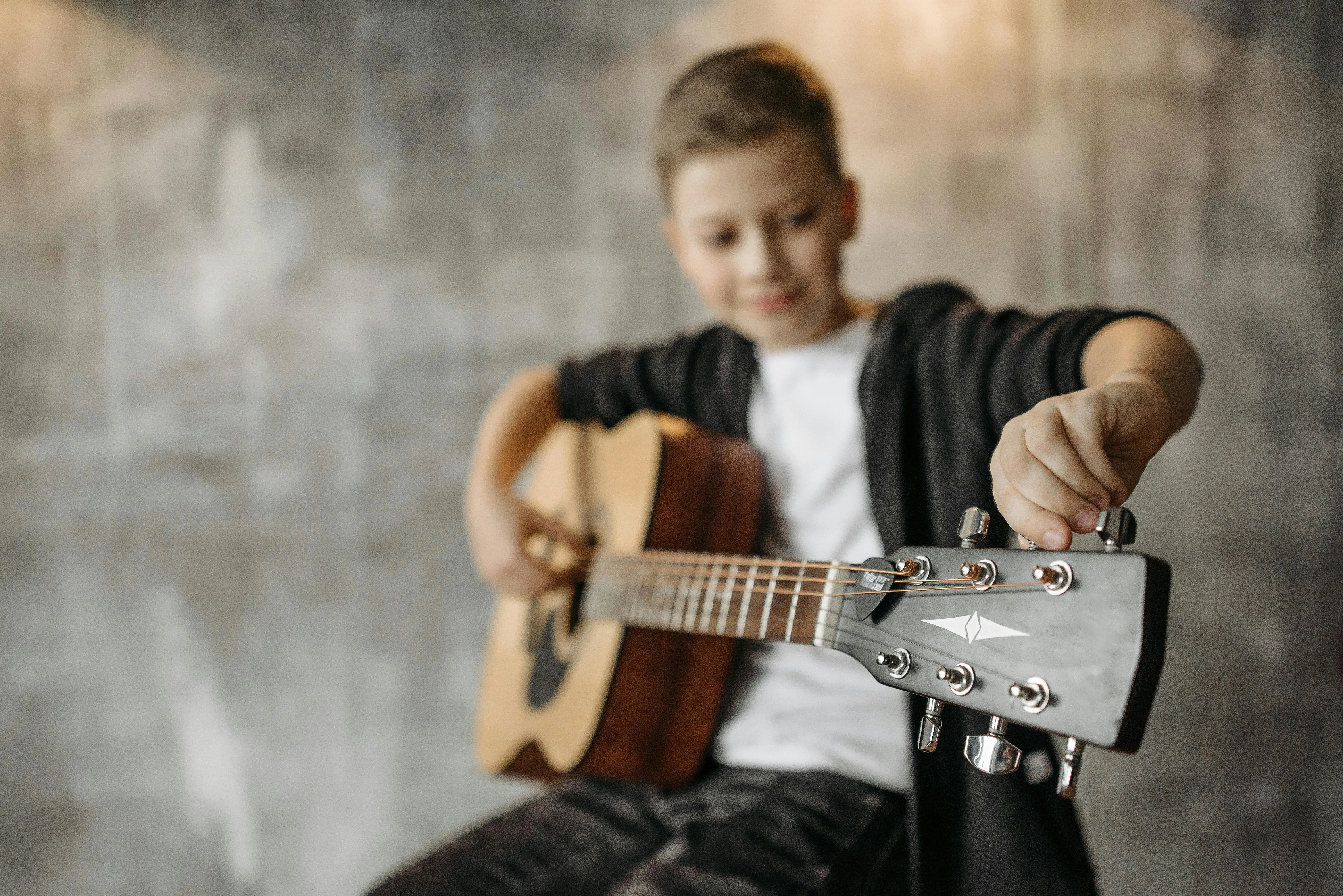 Smiling student tuning his guitar